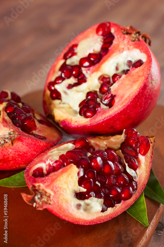 Ripe pomegranate with leaves on a wooden board.
