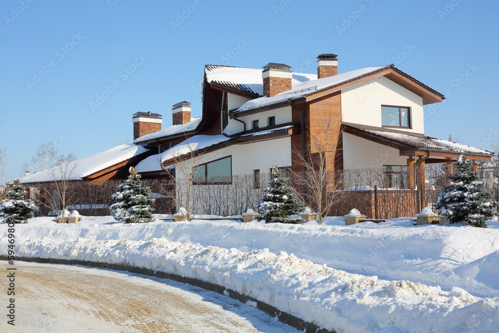 Beautiful two-storey house and trees on sunny frosty winter day.