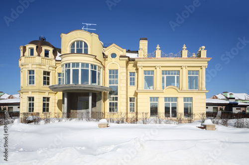 Beautiful two-storey yellow house and bushes on sunny frosty