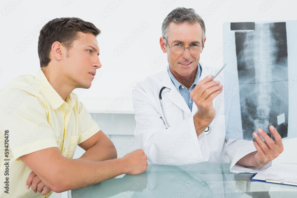 Obraz premium Doctor explaining spine x-ray to patient in office