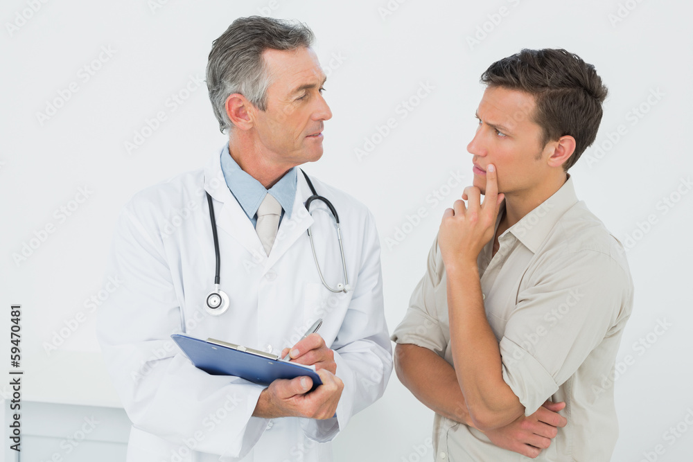Doctor discussing reports with patient in office Doctor discussing reports with patient in office