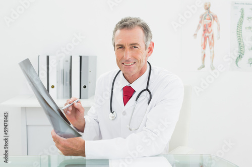 Smiling doctor with x-ray picture of lungs in office