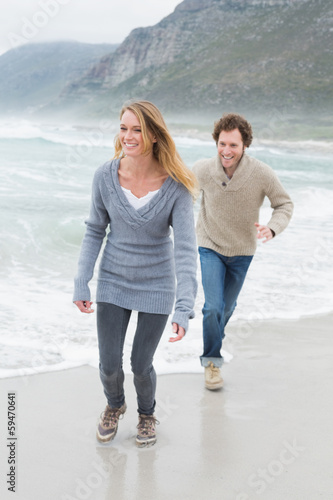 Happy casual young couple running at beach © lightwavemedia