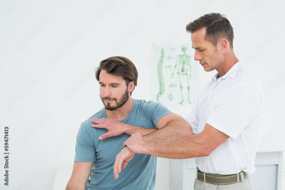 Male physiotherapist stretching a young man's hand Male physiotherapist stretching a young man's hand
