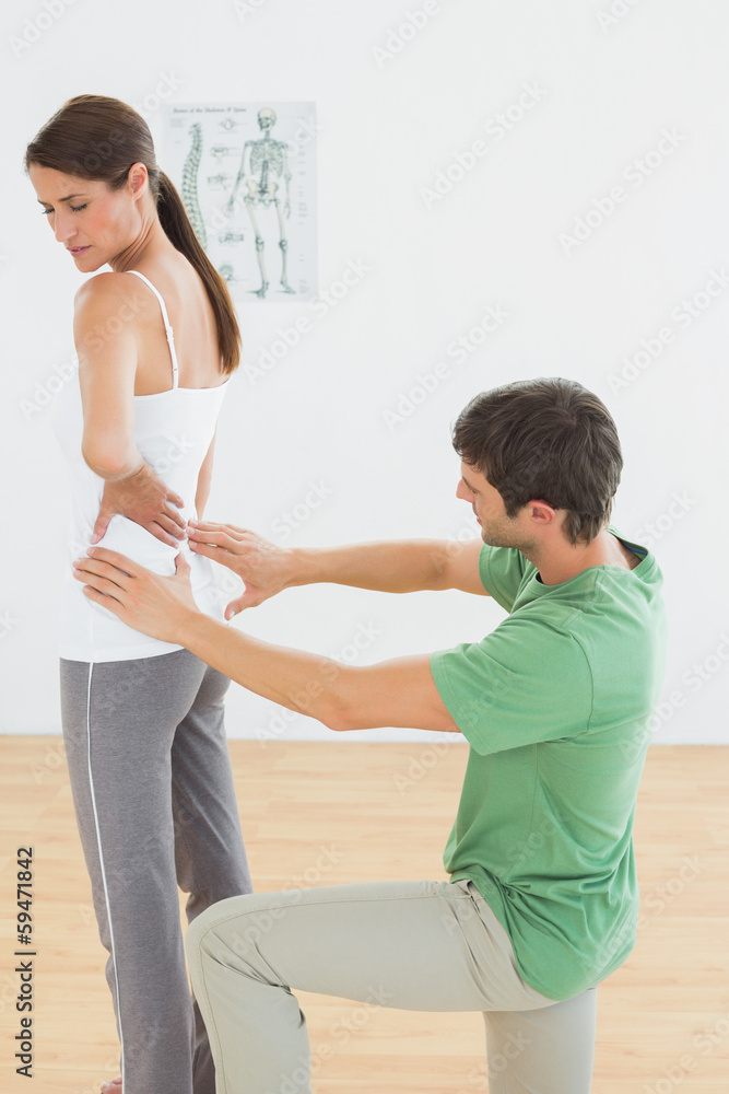 Physiotherapist examining woman's back in medical office Physiotherapist examining woman's back in medical office