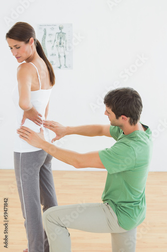 Physiotherapist examining woman's back in medical office