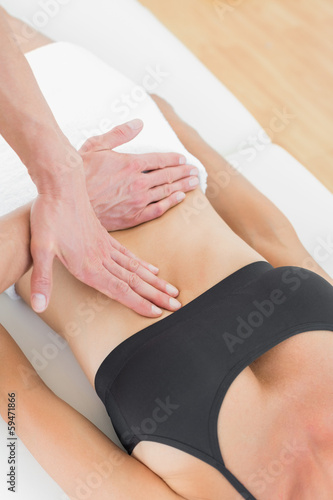 Mid section of a physiotherapist massaging woman s body