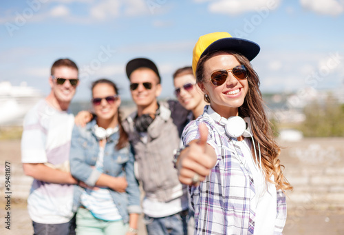 teenage girl with headphones and friends outside © Syda Productions