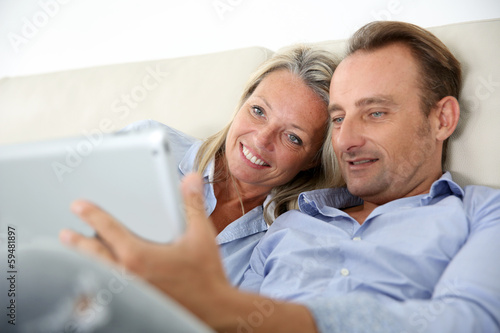 Couple in couch websurfing on the net with pad © goodluz