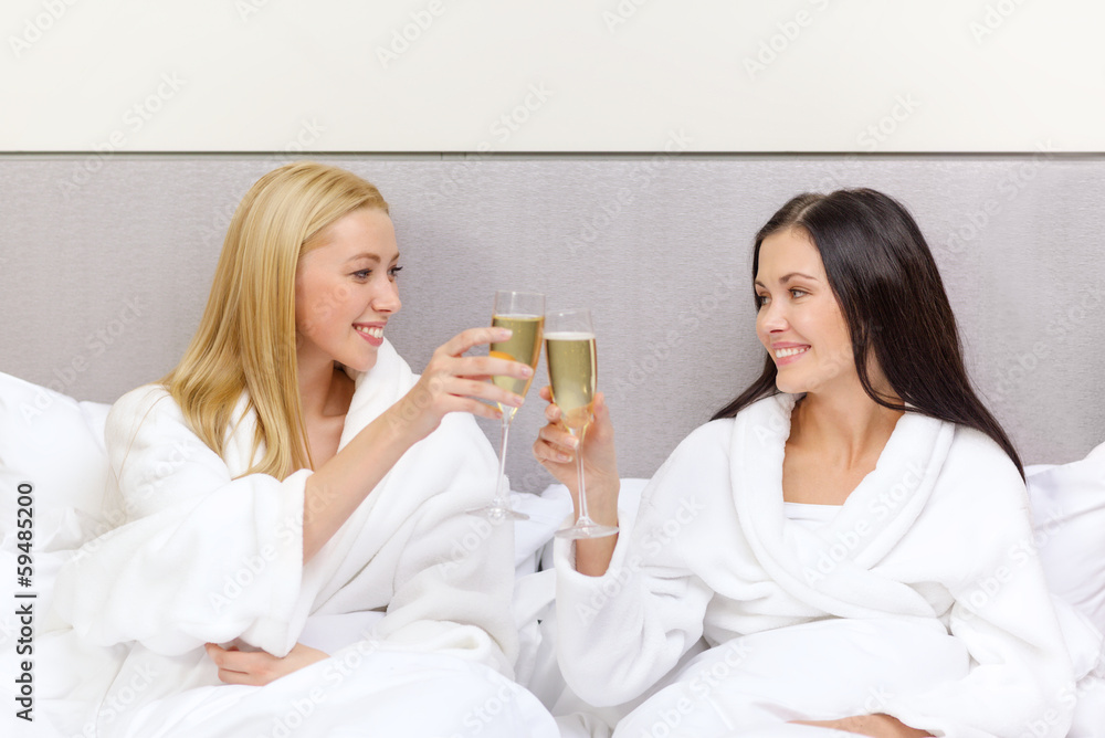 smiling girlfriends with champagne glasses in bed smiling girlfriends with champagne glasses in bed