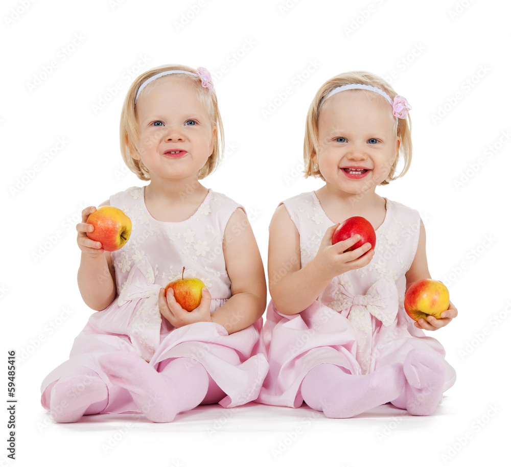 two identical twin girls playing with apples two identical twin girls playing with apples