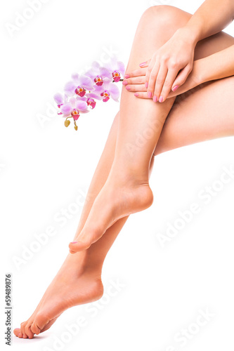 female legs and pink manicure with orchid flower