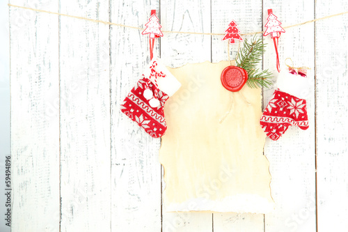Blank sheet with Christmas decor hanging on white wooden wall