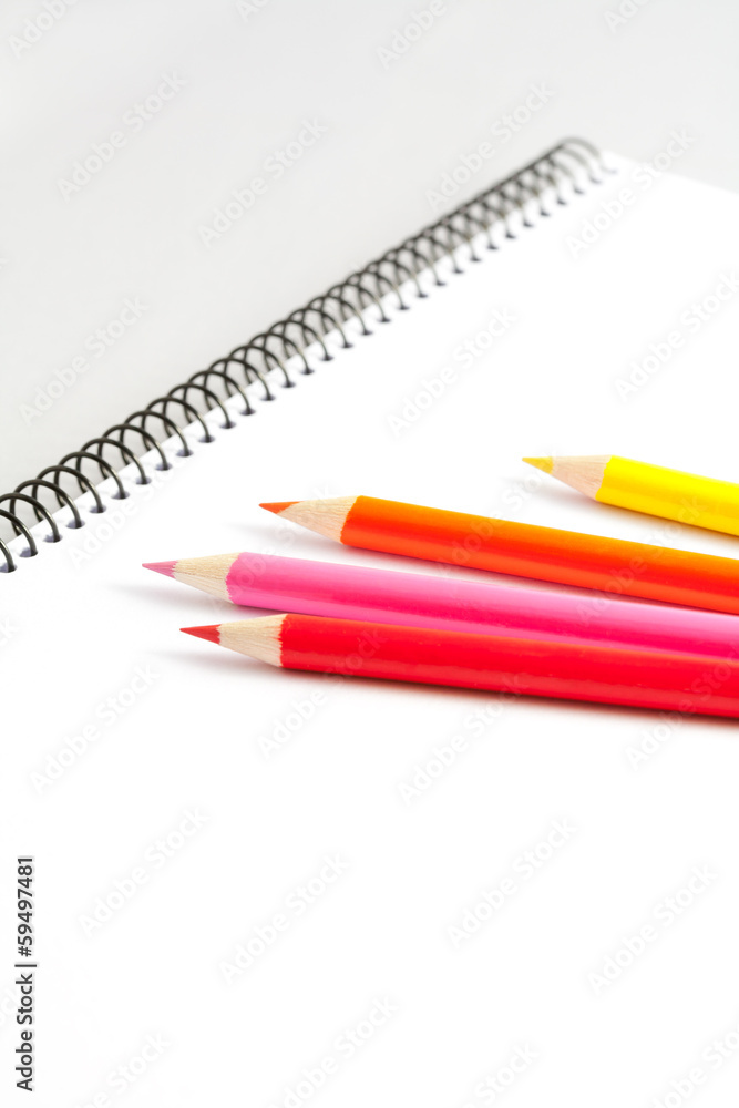 Open sketchbook with clear page with colored pencils on gray background. Open sketchbook with clear page with colored pencils on gray background.