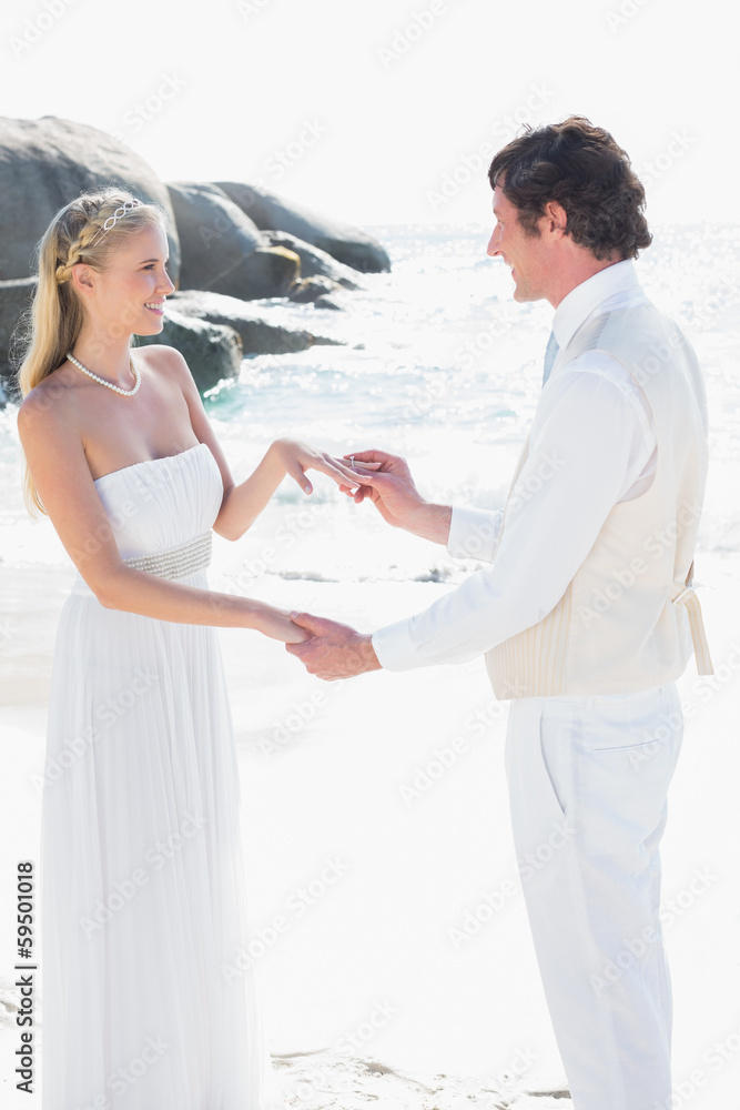 Fototapeta premium Man placing ring on pretty brides finger