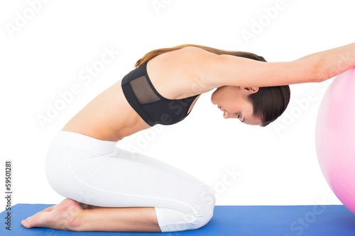 Side view of a fit woman exercising with fitness ball