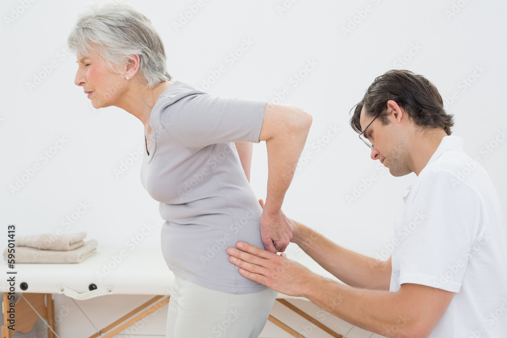 Fototapeta premium Physiotherapist examining senior woman's back