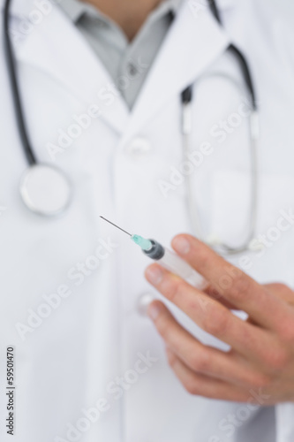 Mid section of a male doctor holding an injection