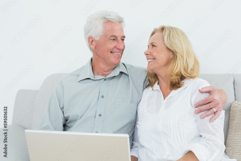 Senior couple with laptop on sofa in a house