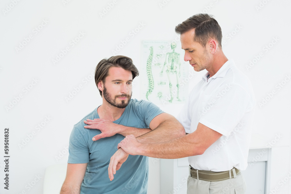Male physiotherapist stretching a young man's hand Male physiotherapist stretching a young man's hand