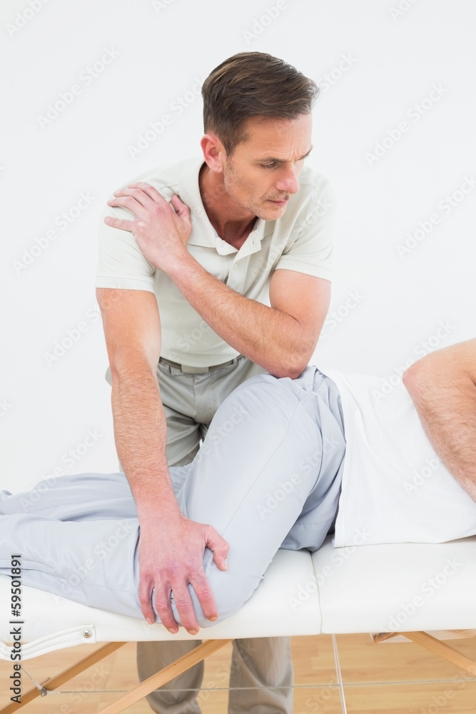 Male physiotherapist examining a young man Male physiotherapist examining a young man