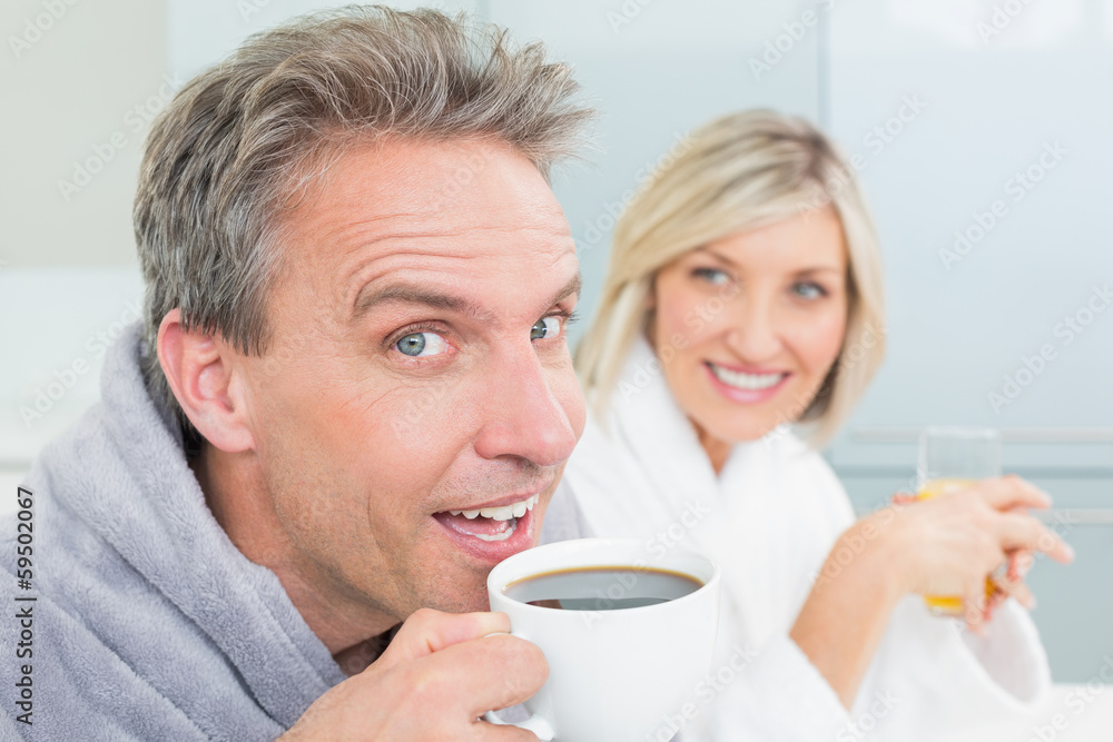 Happy couple in bathrobes with coffee cup and juice