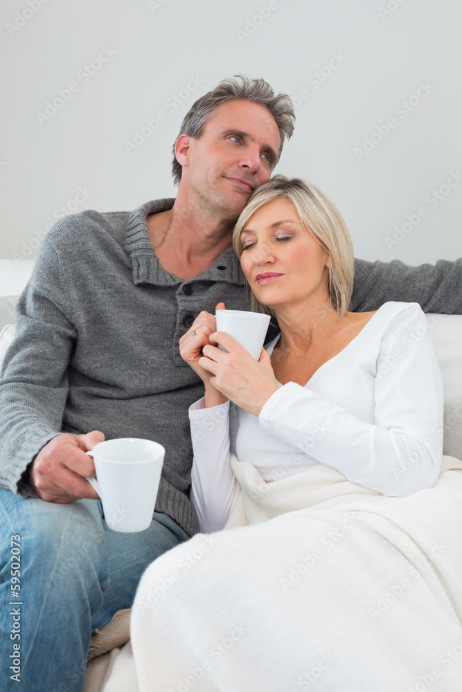 Relaxed couple with coffee cups in living room Relaxed couple with coffee cups in living room