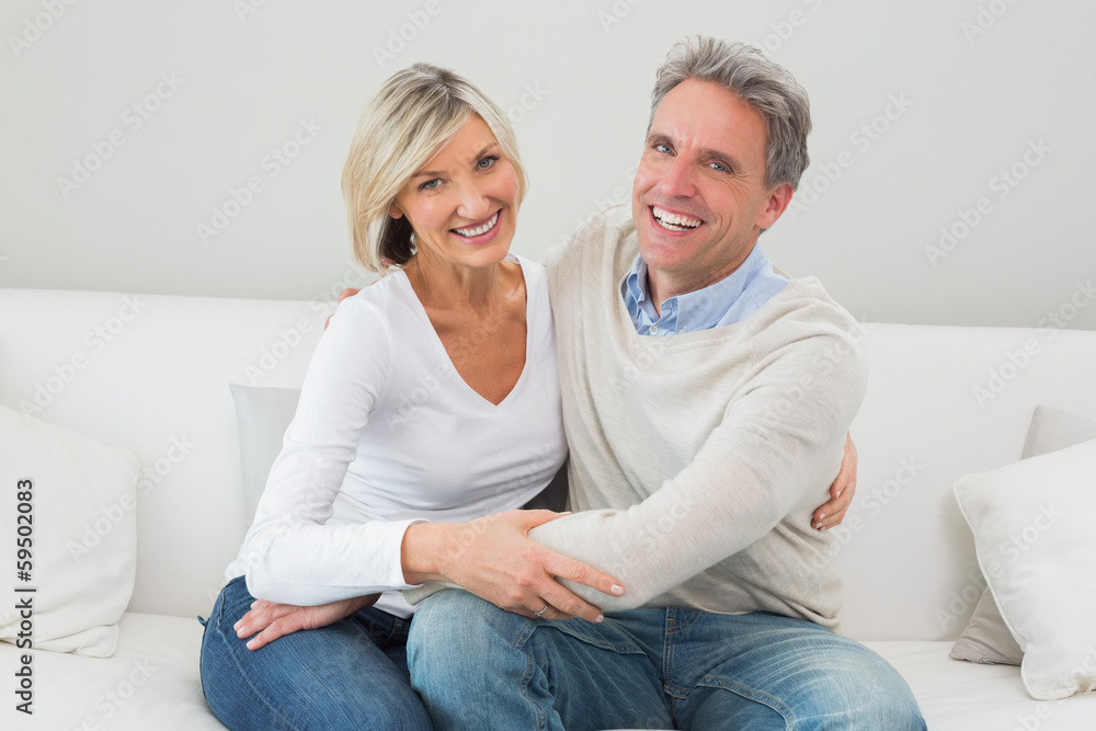 Happy couple embracing on sofa in living room Happy couple embracing on sofa in living room