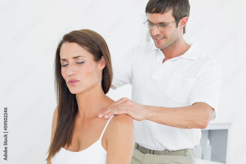 Male chiropractor massaging a young woman's shoulder Male chiropractor massaging a young woman's shoulder