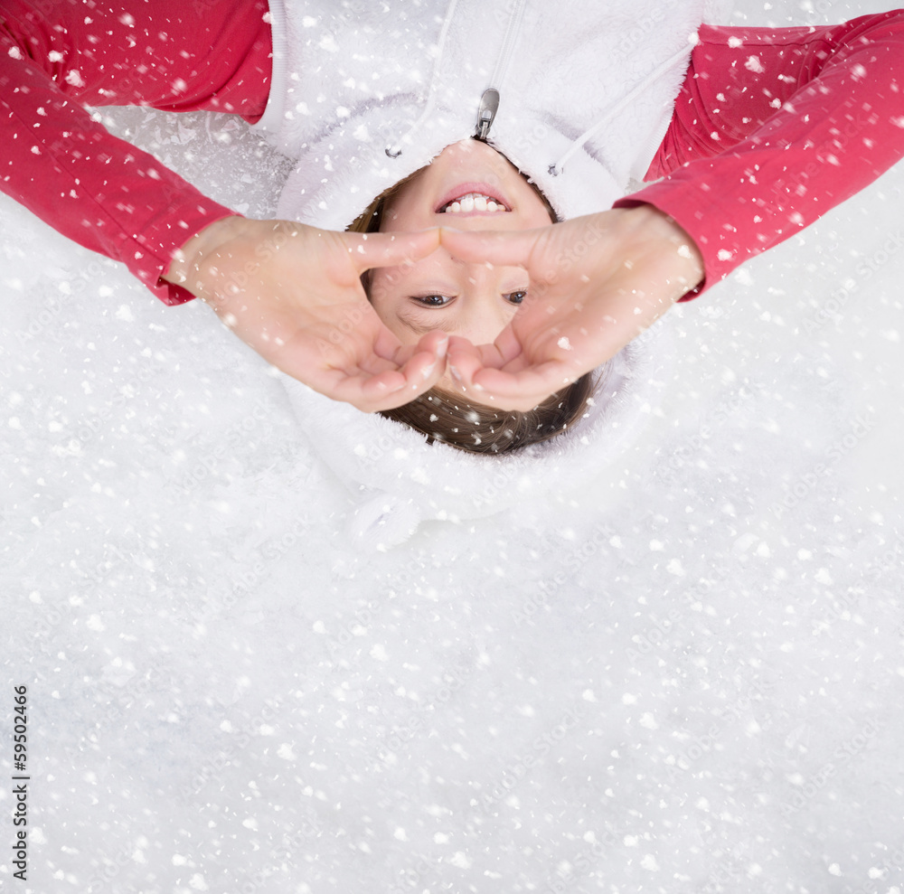 Fototapeta premium Kind liegt im Winter im Schnee mit Herz