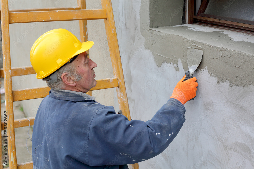 Worker spreading mortar over polystyrene insulation with trowel Worker spreading mortar over polystyrene insulation with trowel