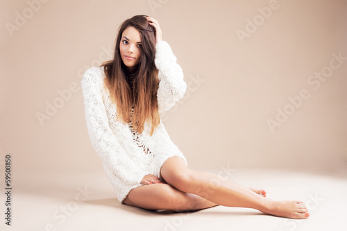 Tender woman in white woolen sweater against beige background