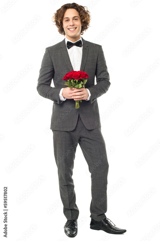 Groom in tuxedo posing with a bouquet