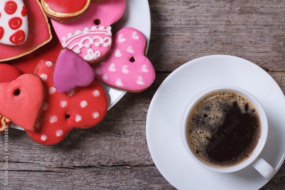 Black coffee and colorful heart cookies on a wooden table