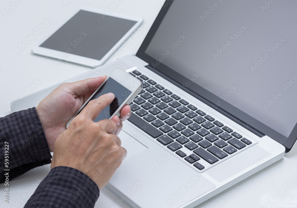 Man hand working with smartphone with computer background. Man hand working with smartphone with computer background.