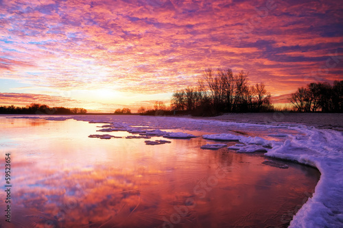 Winter landscape with lake and sunset fiery sky. photo