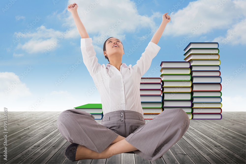 Composite image of cheering businesswoman sitting cross legged Composite image of cheering businesswoman sitting cross legged