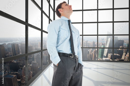 Composite image of serious businessman standing with hands in po