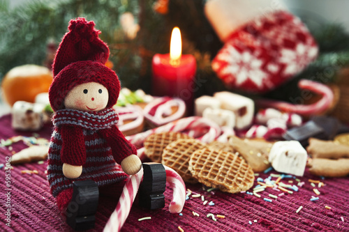 Wooden smiling doll with sweets on christmas background