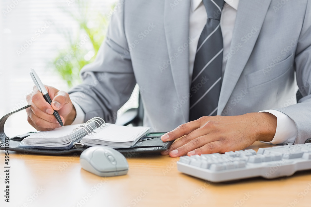 Mid section of a businessman writing in diary Mid section of a businessman writing in diary