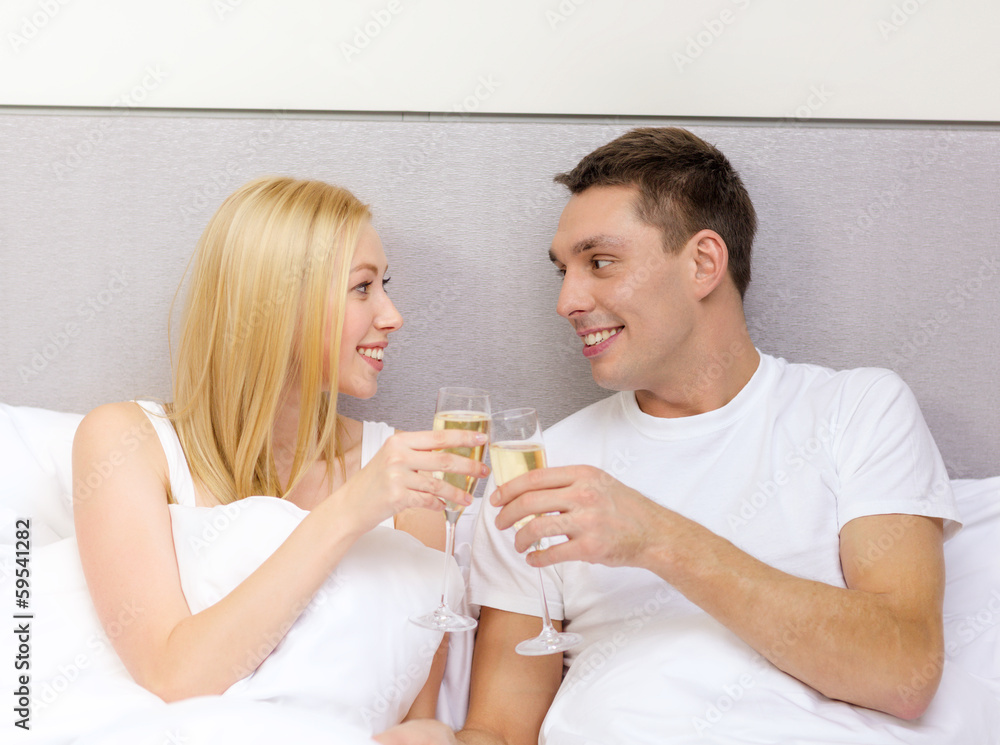smiling couple with champagne glasses in bed smiling couple with champagne glasses in bed