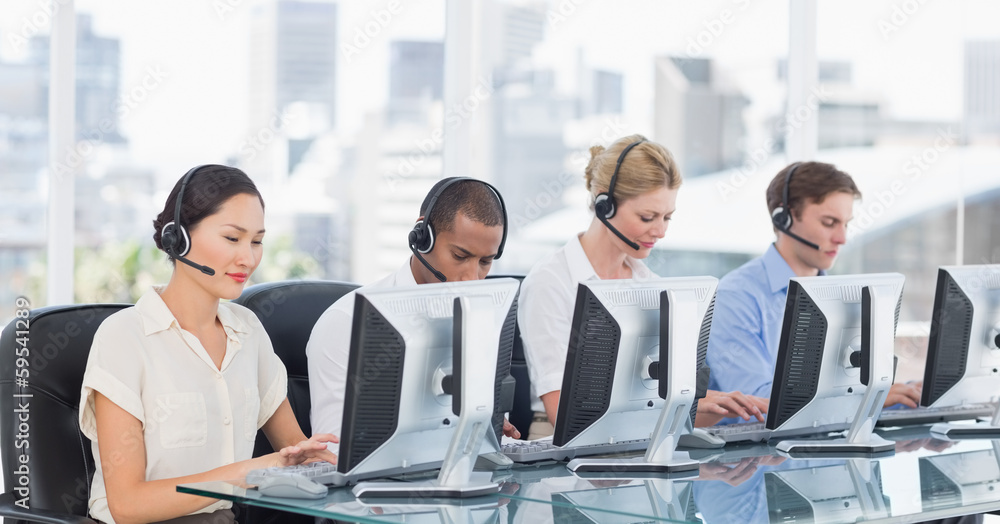 Colleagues with headsets using computers at desk Colleagues with headsets using computers at desk