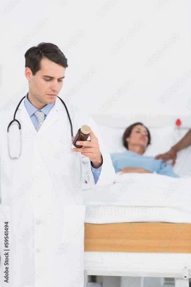 Doctor holding a bottle of pills with patient in hospital Doctor holding a bottle of pills with patient in hospital