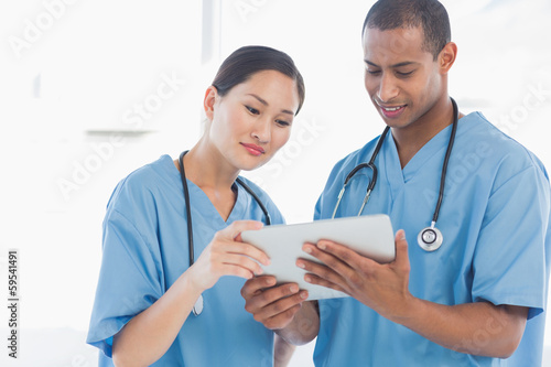 Surgeons looking at digital tablet in hospital