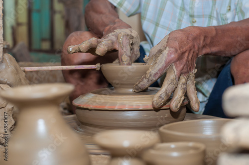 A man shapes pottery as it turns on a wheel