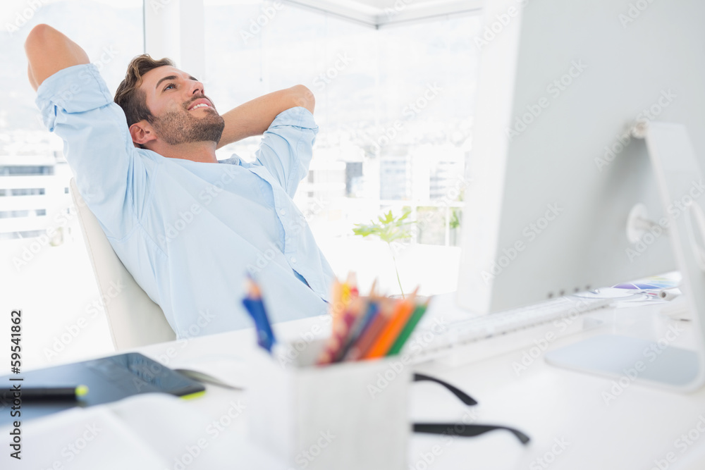 Casual young man resting with hands behind head in office Casual young man resting with hands behind head in office