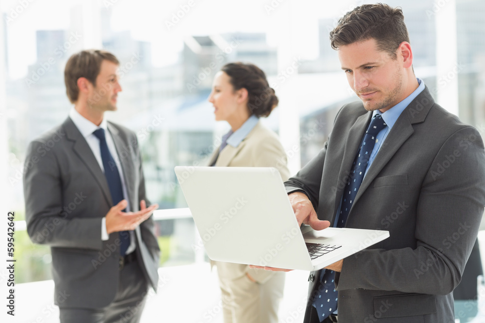 Businessman using laptop with colleagues discussing in office