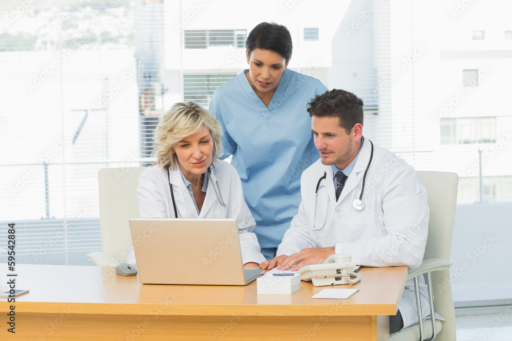 Three concentrated doctors using laptop together