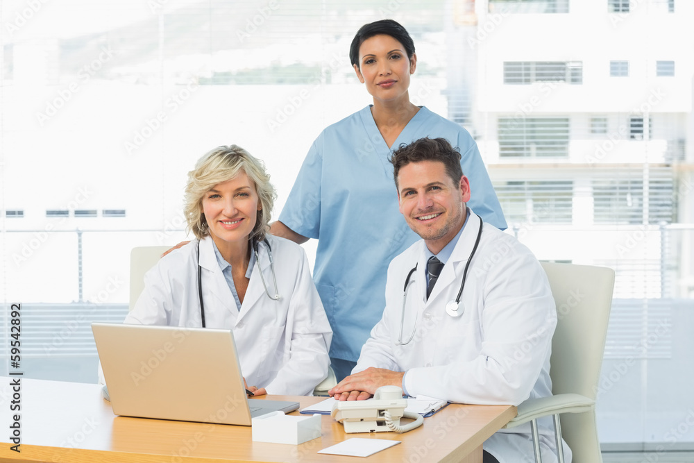 Fototapeta premium Smiling doctors with laptop at medical office
