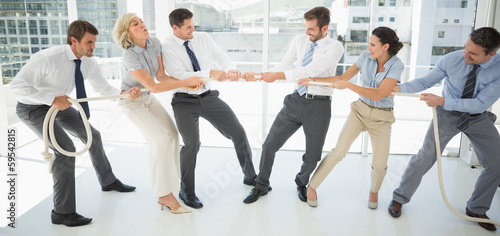 Foto Business people playing tug of war in office